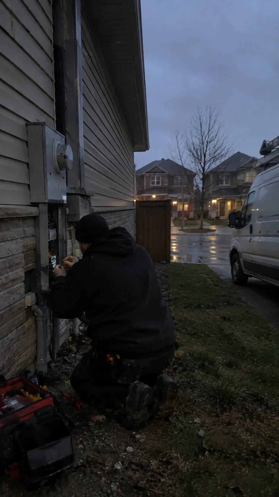 Electrician working near an electrical panel in evening light