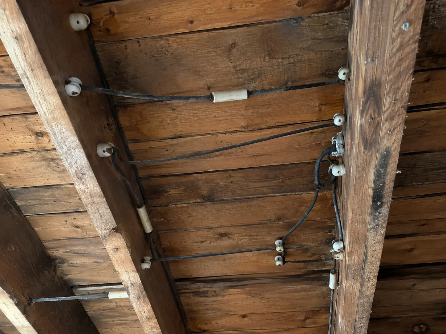 Knob and tube wiring with porcelain knobs and tubes on exposed basement joists
