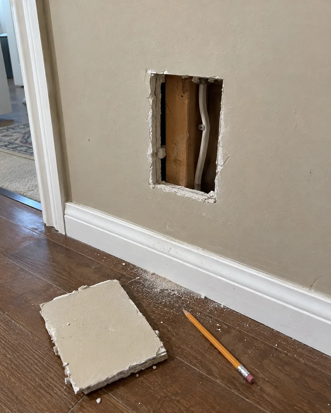 Small access opening in a wall prepared for residential electrical rewiring