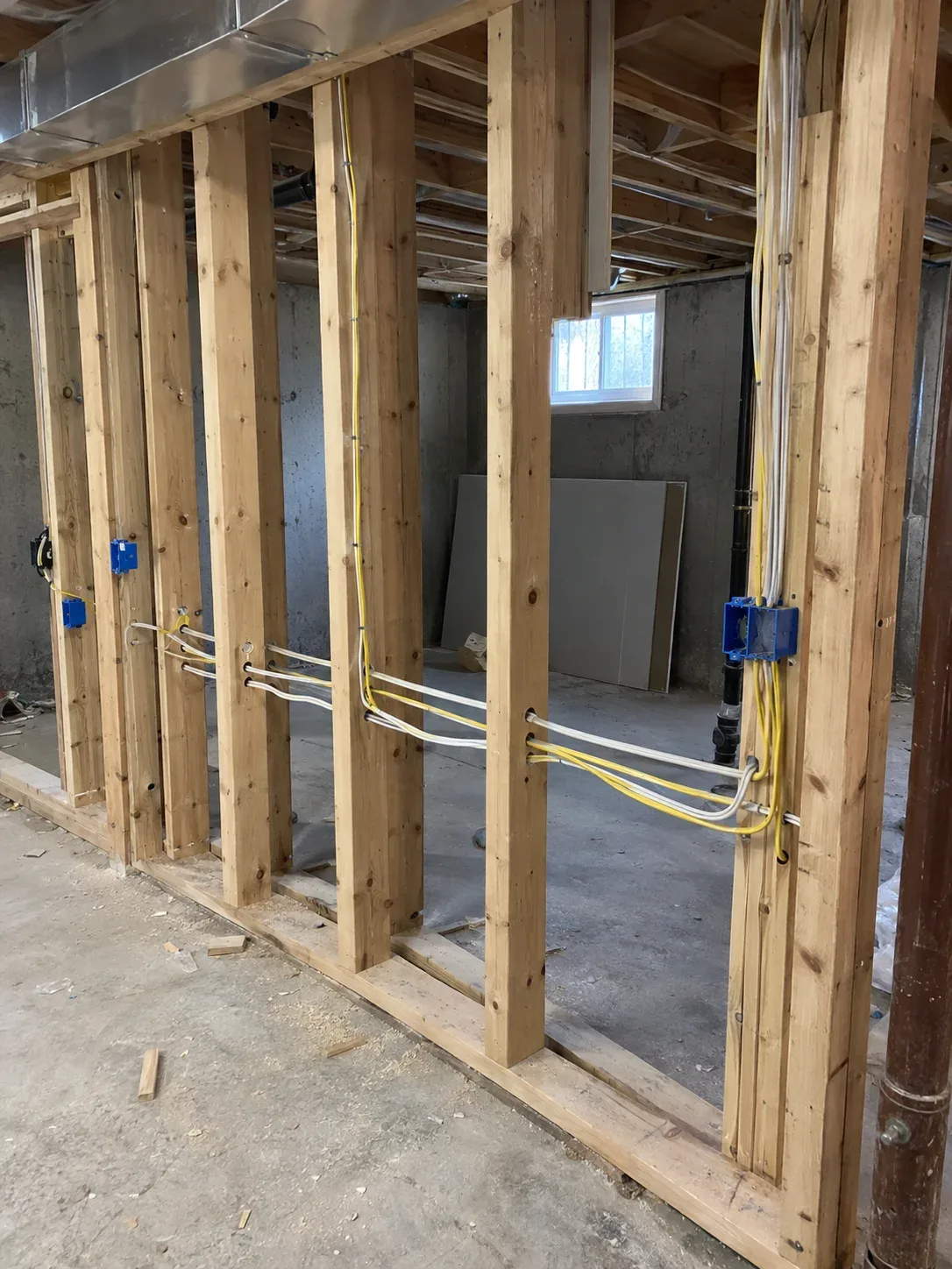 Open basement framing with neat new electrical wiring installed before drywall