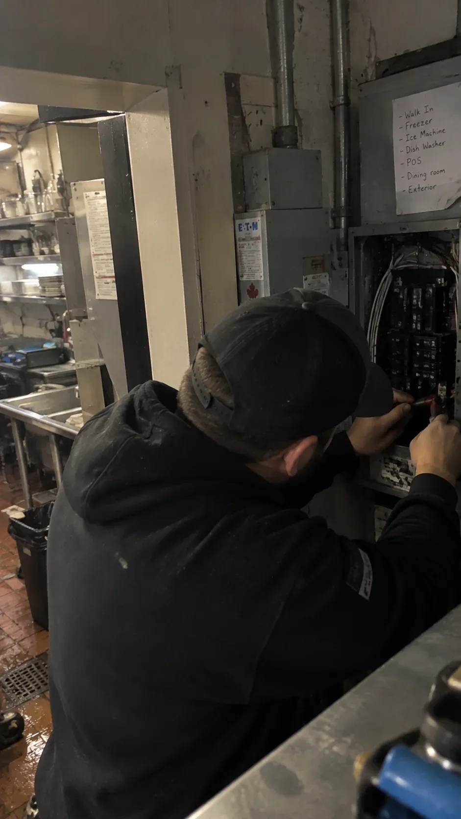 Electrician working on a commercial electrical panel inside a business